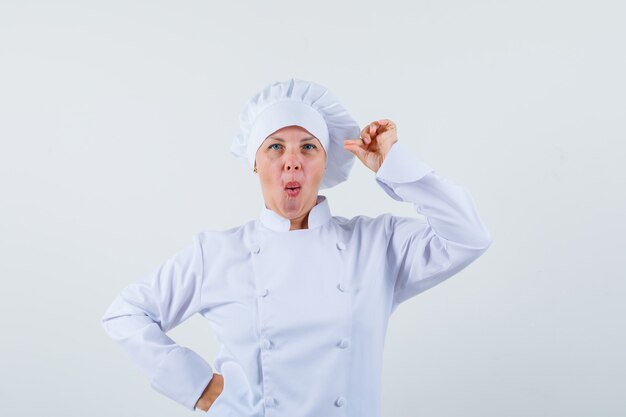 woman chef in white uniform posing while pouting lips and looking focused