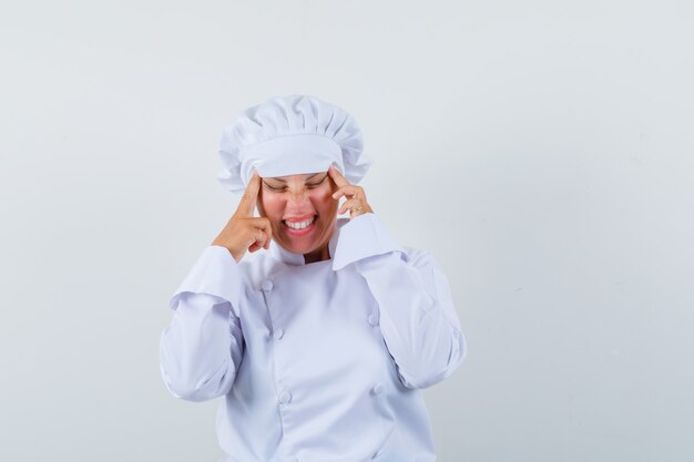 woman chef in white uniform pulling skin on her temples and looking tired