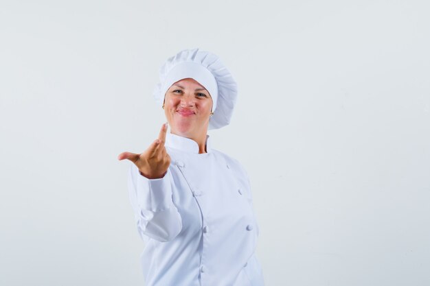 woman chef in white uniform raising hand in questioning manner and looking energetic