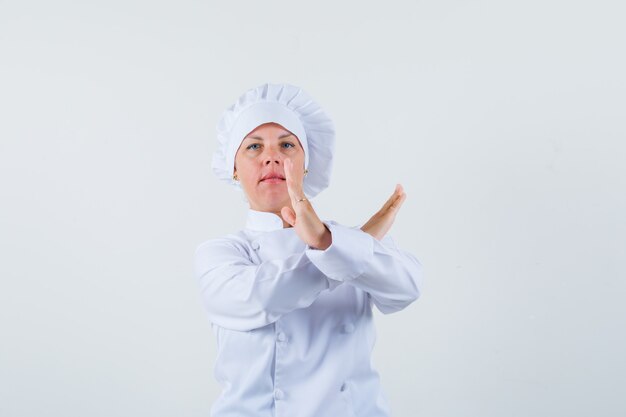 woman chef in white uniform showing closed gesture and looking serious