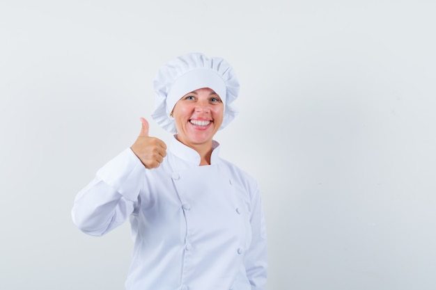 Chef donna in uniforme bianca che mostra il pollice in su e sembra allegra