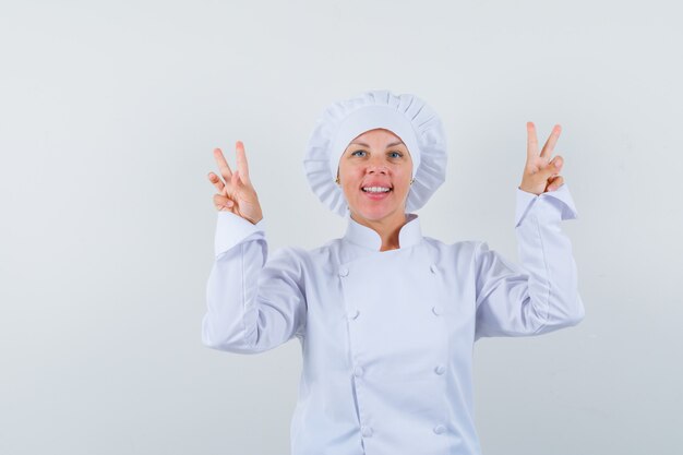 흰색 유니폼 V 기호를 표시하고 자신감을 찾고 여자 요리사