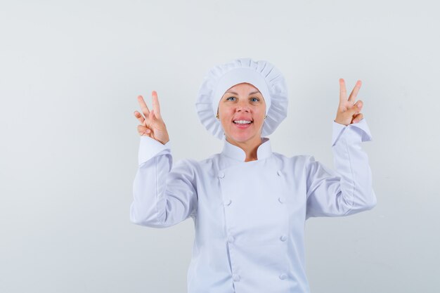 woman chef in white uniform showing V-sign and looking confident