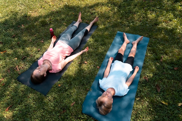 Foto gratuita donna e bambino che fanno yoga a tutto campo