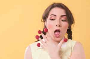 Free photo woman chocking while having raspberries on fingers