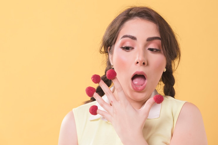 Free Photo woman chocking while having raspberries on fingers