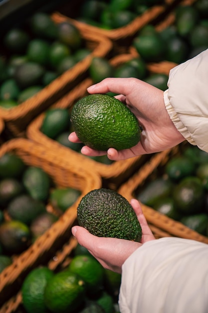 Una donna sceglie un avocado in un negozio di alimentari