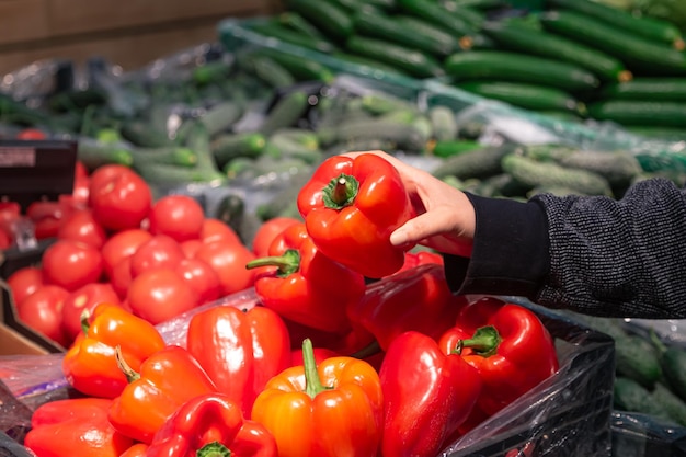 Free photo a woman chooses bell papers at a grocery store