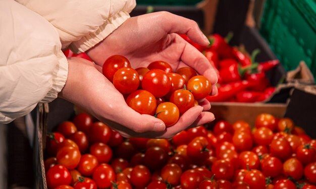 A woman chooses cherry tomatoes in a grocery store closeup