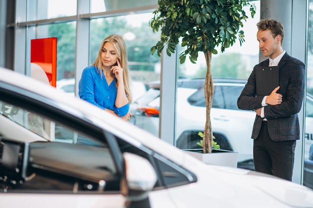 Foto gratuita donna che sceglie un'automobile in una sala d'esposizione dell'automobile