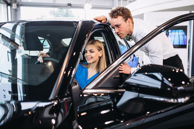 Foto gratuita donna che sceglie un'automobile in una sala d'esposizione dell'automobile