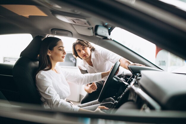 車のショールームで車を選ぶ女性