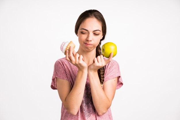 Woman choosing between cupcake and apple