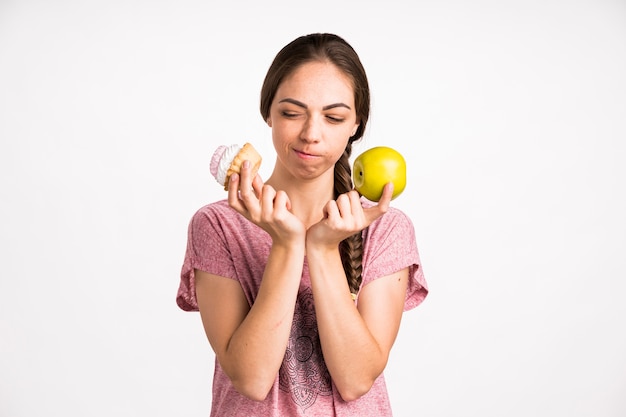 Женщина, выбирающая кекс над яблоком