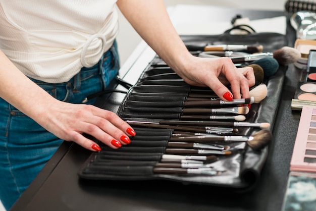 Foto gratuita donna che sceglie la spazzola di trucco dall'insieme