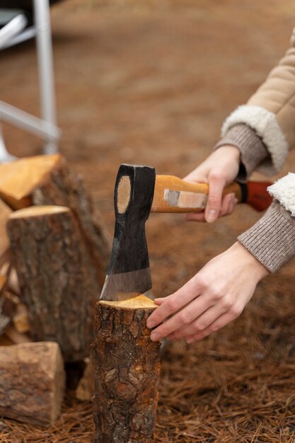 焚き火のために斧で木を切る女性