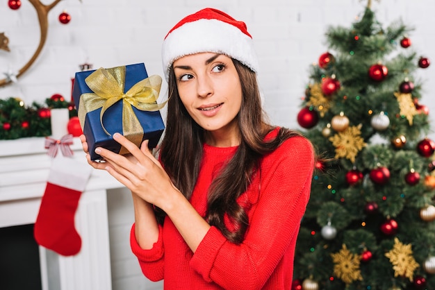 선물 상자를 들고 크리스마스 모자에있는 여자