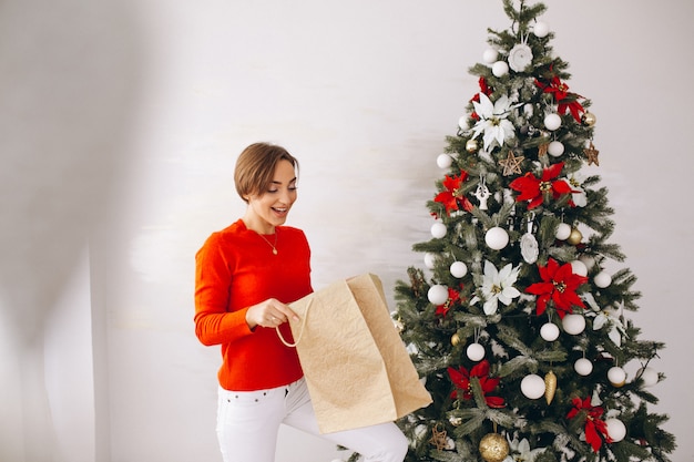 Woman on christmas with gifts by christmas tree