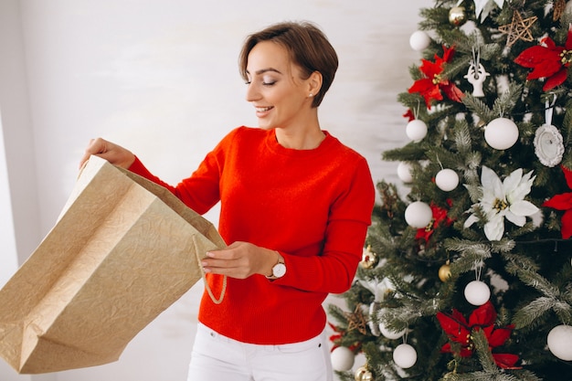 Woman on christmas with gifts by christmas tree