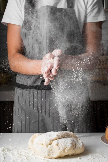 Woman clapping hands with flour over dough