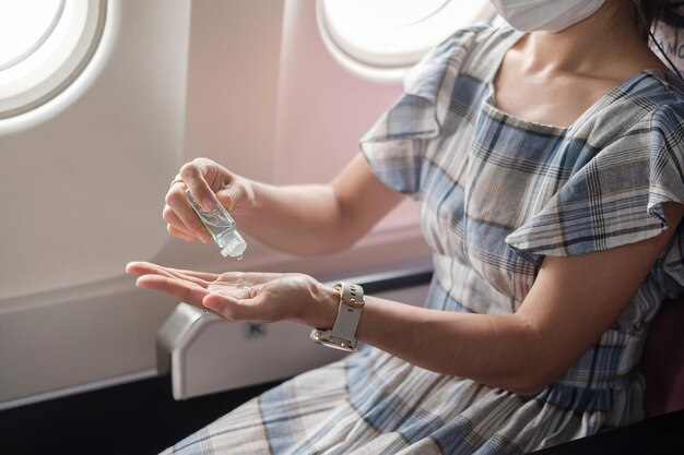 女性​は​飛行機​や​公共​交通​機関​で​アルコール​ゲル​消毒剤​で​手​を​きれい​に​し​、​コロナ​ウイルス​感染症​を​予防します​。 covid​-​19​の​概念​の​下​で​の​新しい​通常​、​安全​および​旅行​輸送