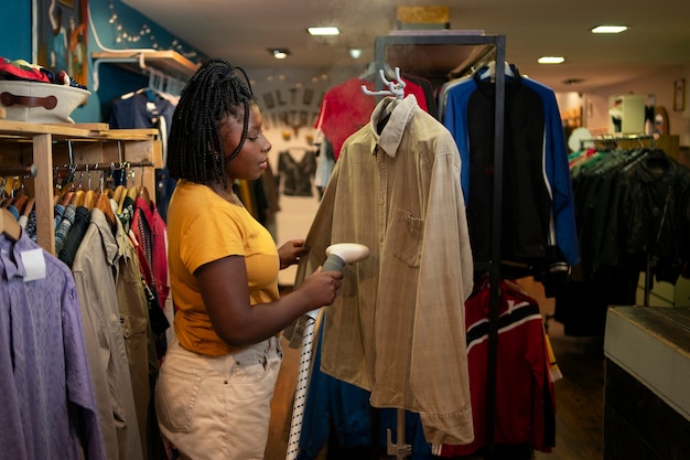 Free photo woman cleaning clothing in thrift store