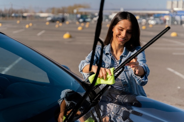 Женщина, чистящая свою машину на улице