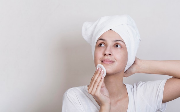 Free photo woman cleaning her face with copy space