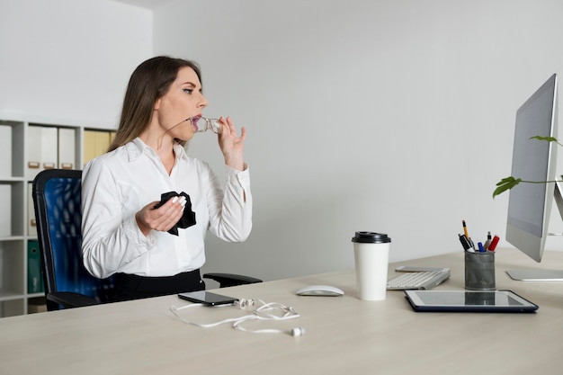 Free photo woman cleaning her glasses at work