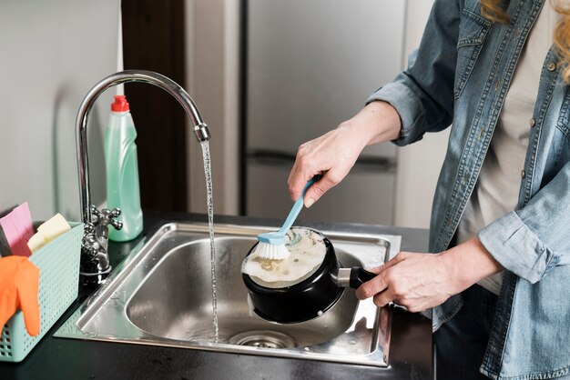 Woman cleaning a pot in the sink with brush