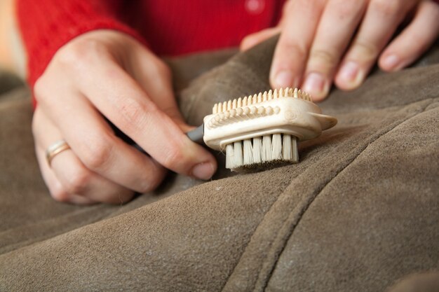 Woman cleaning a sheepskin with whisk broom