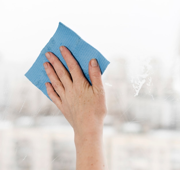 Free photo woman cleaning window with rag