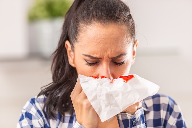 Женщина прочищает нос, не подозревая о кровотечении, появившемся на ткани.