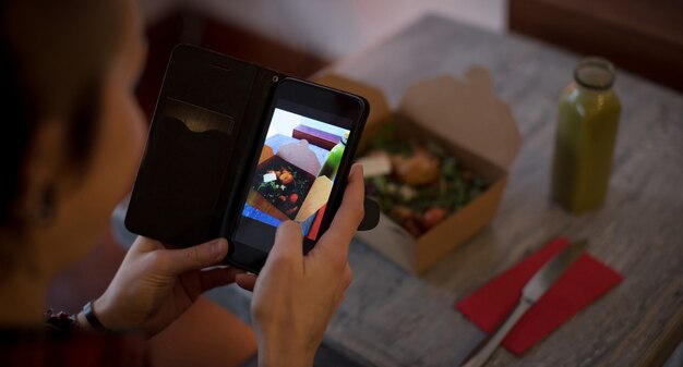 Woman clicking a photo of salad from mobile phone