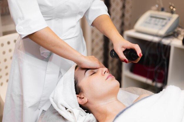 Woman client in salon receiving manual facial massage from beautician