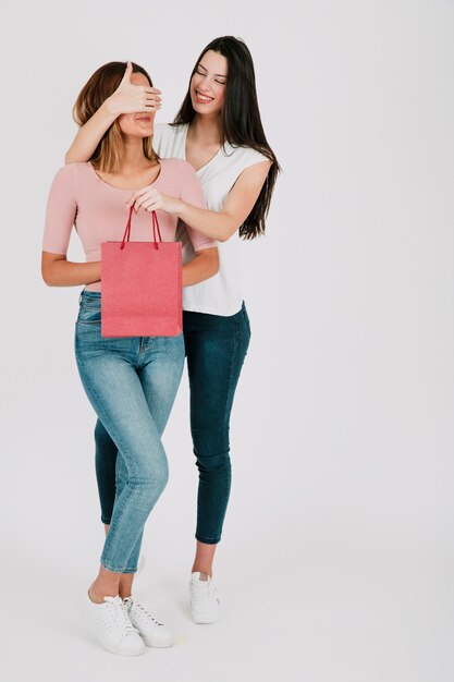 Woman closing eyes to girlfriend and surprising her