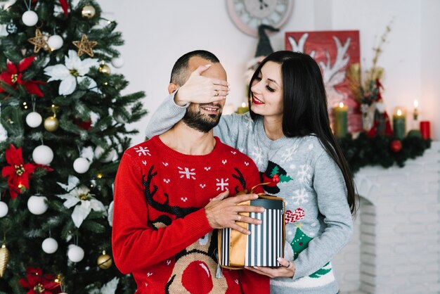 Woman closing eyes to man with gift