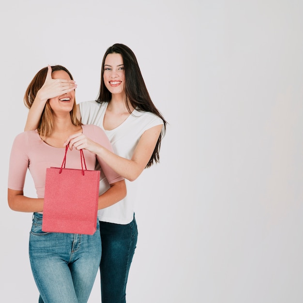 Woman closing eyes and surprising girlfriend