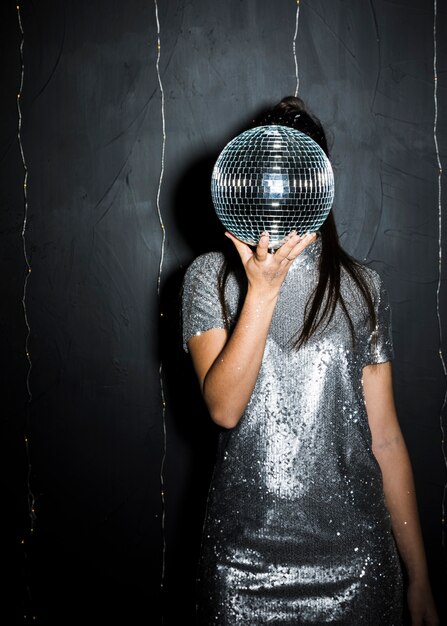 Woman closing face by disco ball