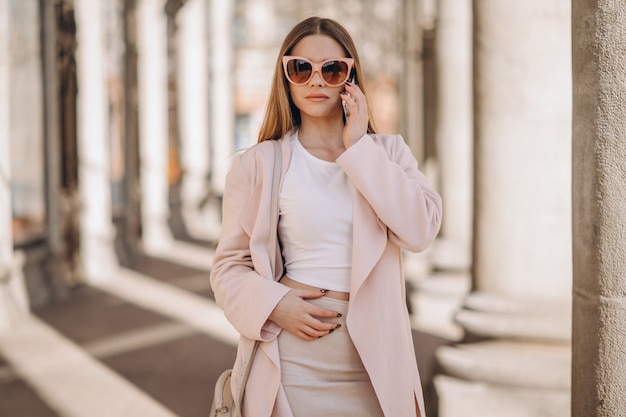 Woman in coat walking in the street and talking on the phone