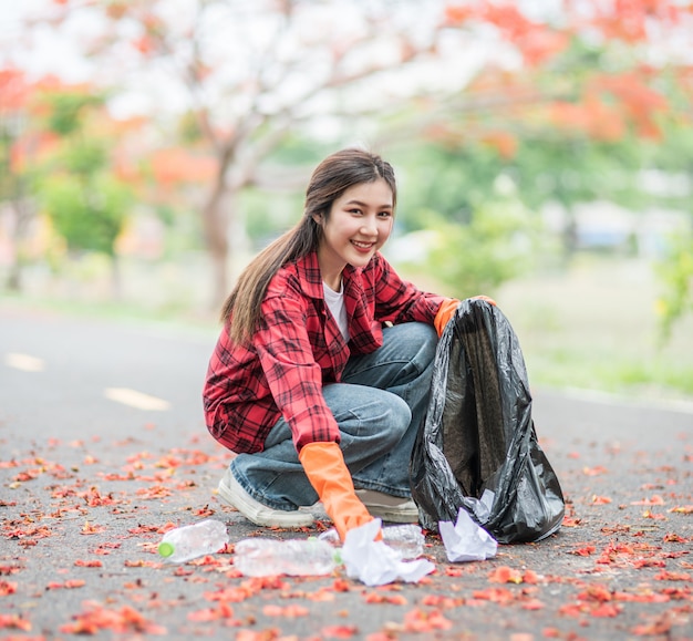 Woman collecting garbage in a black bag.