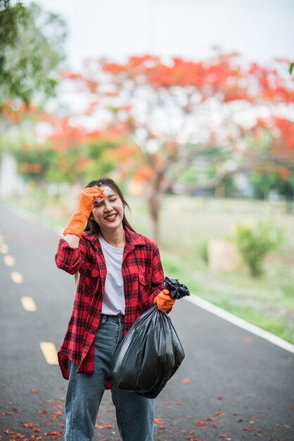 Woman collecting garbage in a black bag.