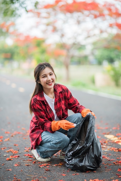 Woman collecting garbage in a black bag.