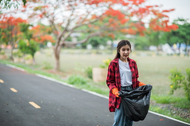 Free photo woman collecting garbage in a black bag.