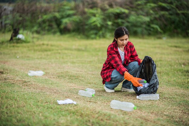 Woman collecting garbage in a black bag.