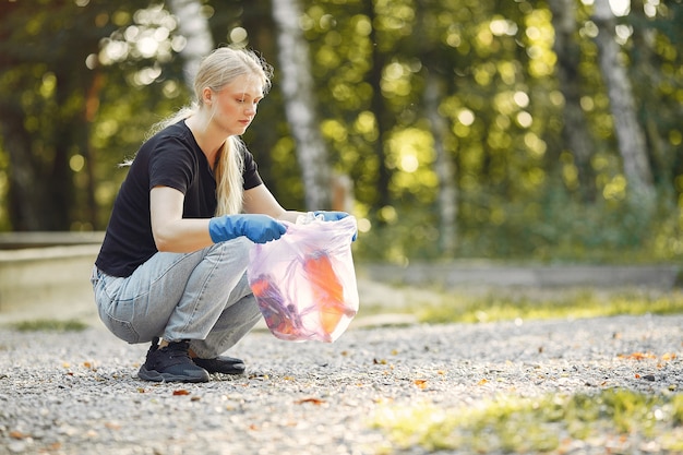 Free photo woman collects garbage in garbage bags in park