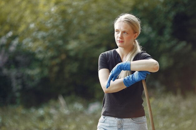 Woman collects leaves and cleans the park