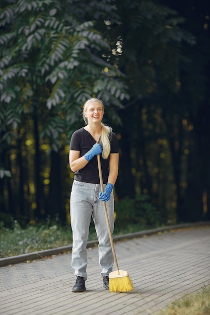 Woman collects leaves and cleans the park