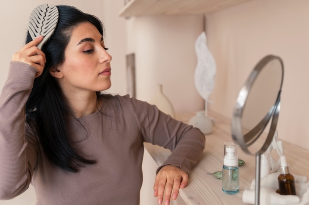 Foto gratuita donna che pettina i capelli durante la sua routine di bellezza