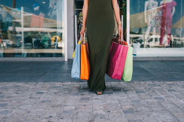 Женщина выходит из магазина и держит сумки